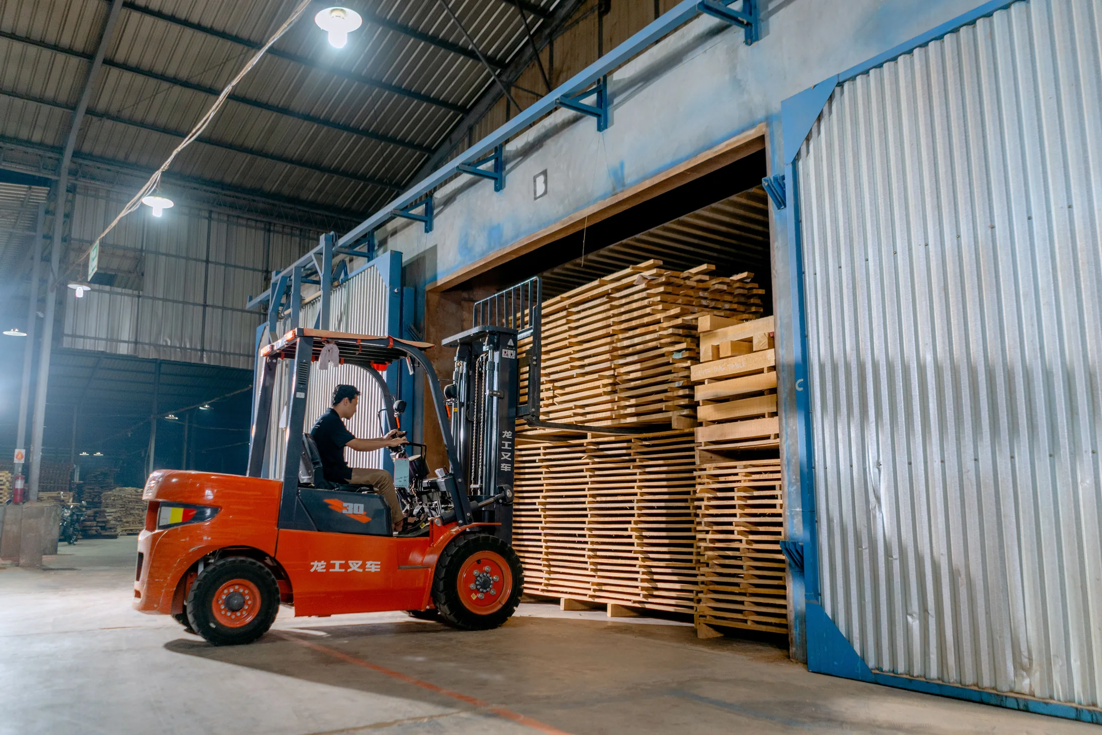 Warehouse worker operating a forklift near stacked pallets
